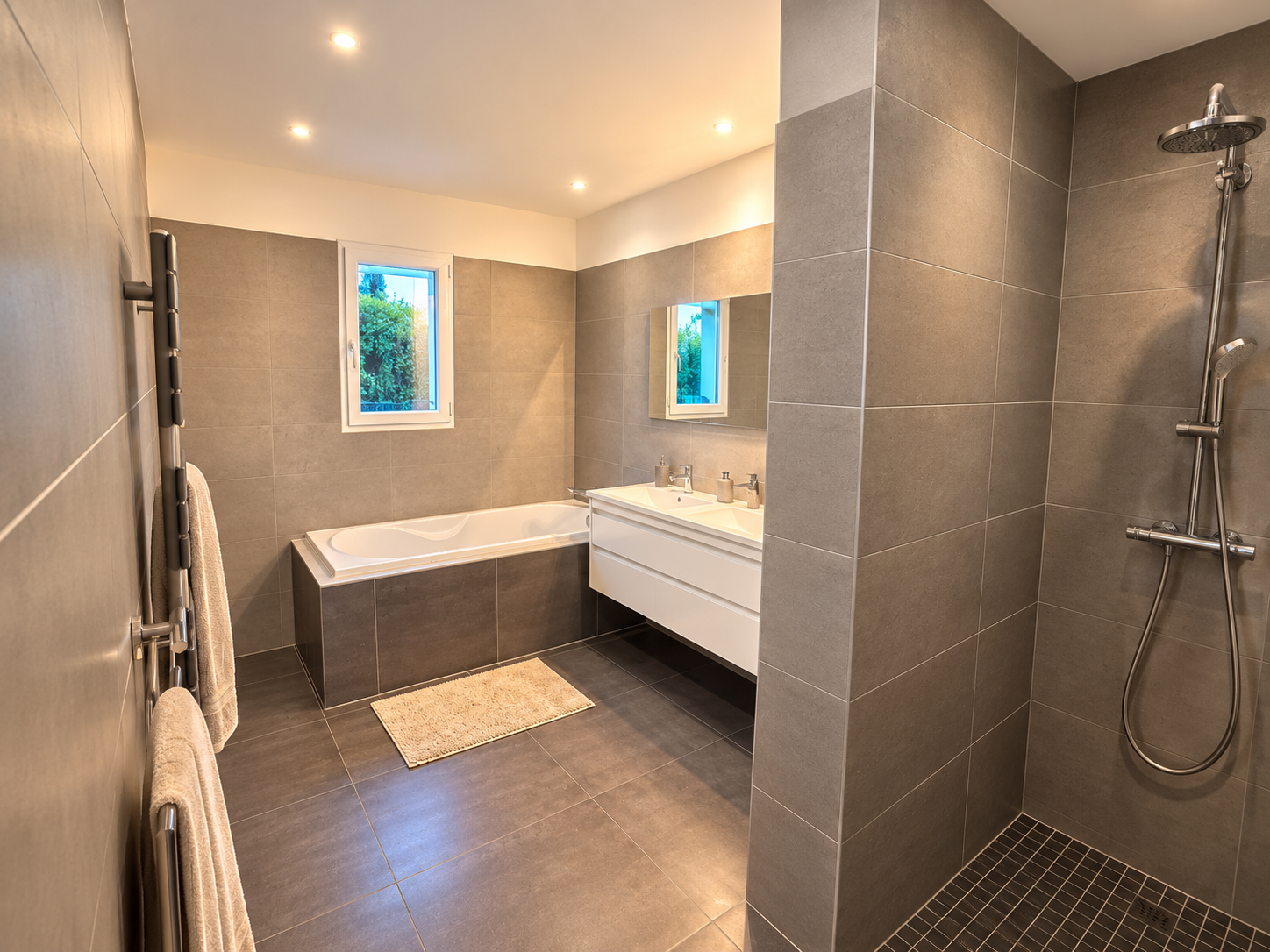 La salle de bain avec baignoire, douche à l'italienne et double vasque