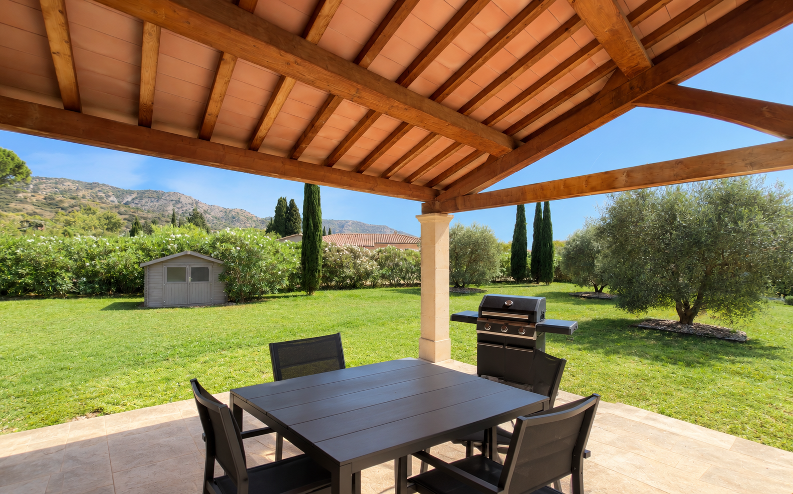La table de repas sous la terrasse couverte, vue sur le jardin et le Luberon